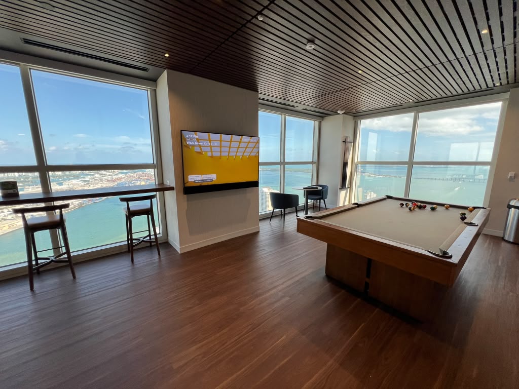 Amenity lounge with a pool table, floor to ceiling glazing and a wall display