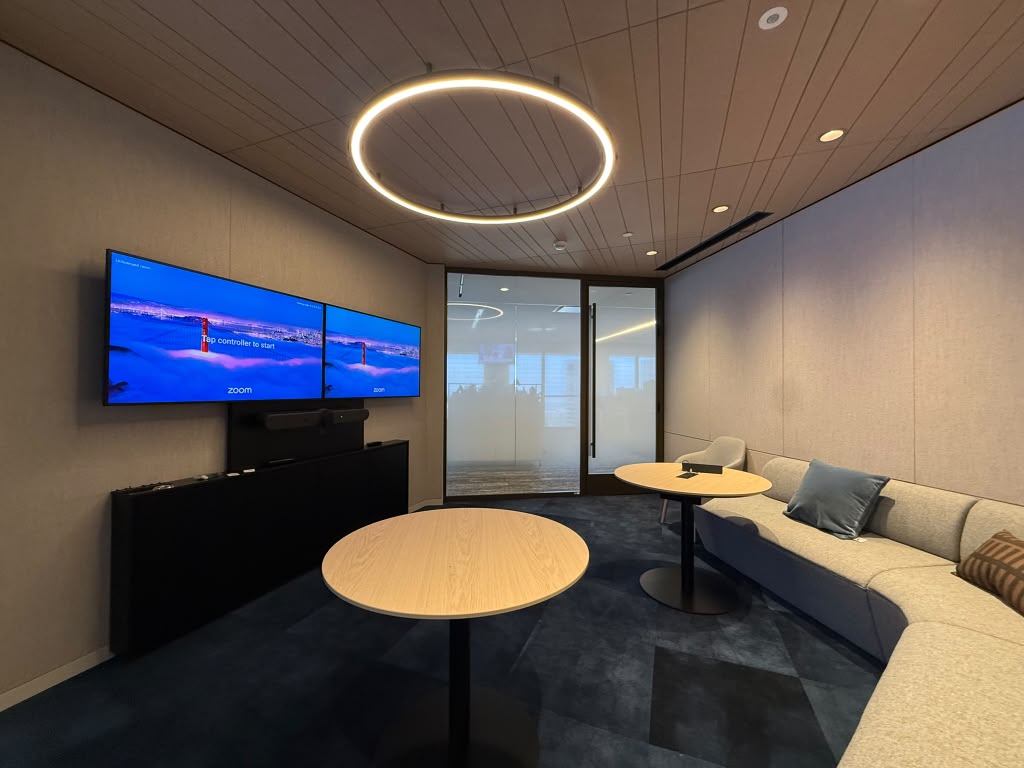 Collaboration room with dual displays, banquette seating and a ring pendant