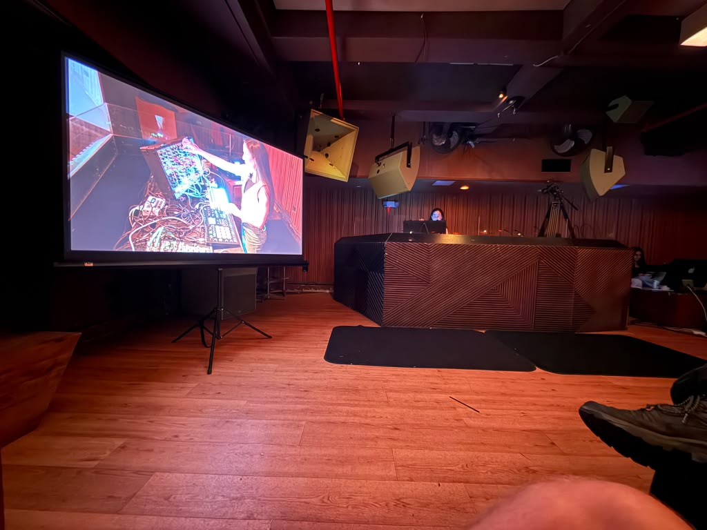 Live venue with a projection screen, DJ booth and flown loudspeakers