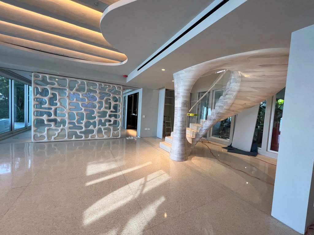Modern residence with a curved stone staircase, terrazzo floor and a decorative screen wall