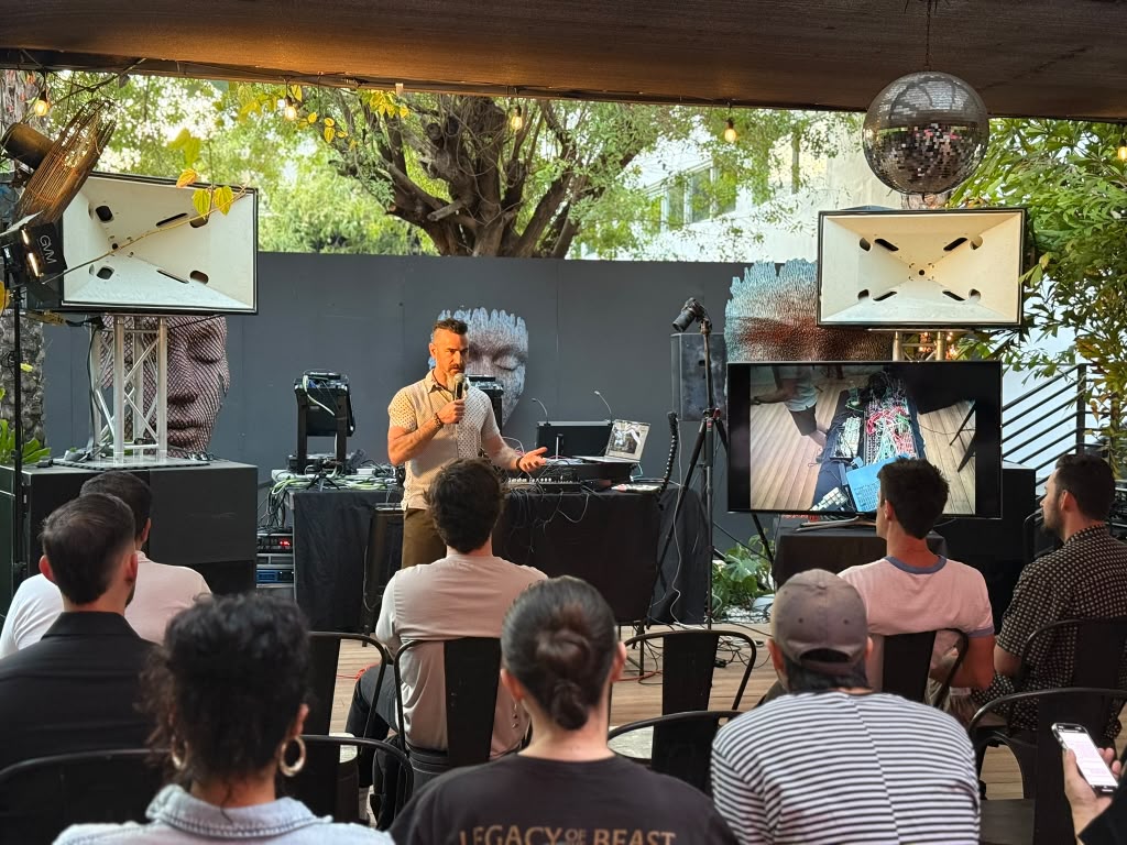 Outdoor presentation with a seated audience, displays either side and a mirror ball overhead