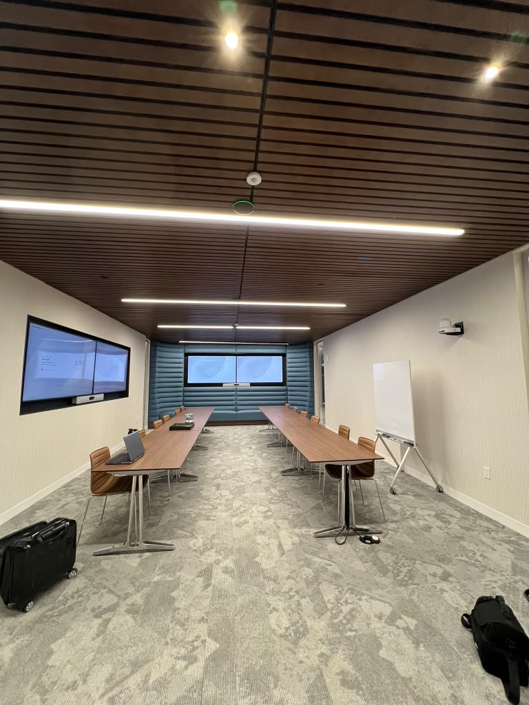 Training room with long tables, dual displays, a projection screen and a whiteboard